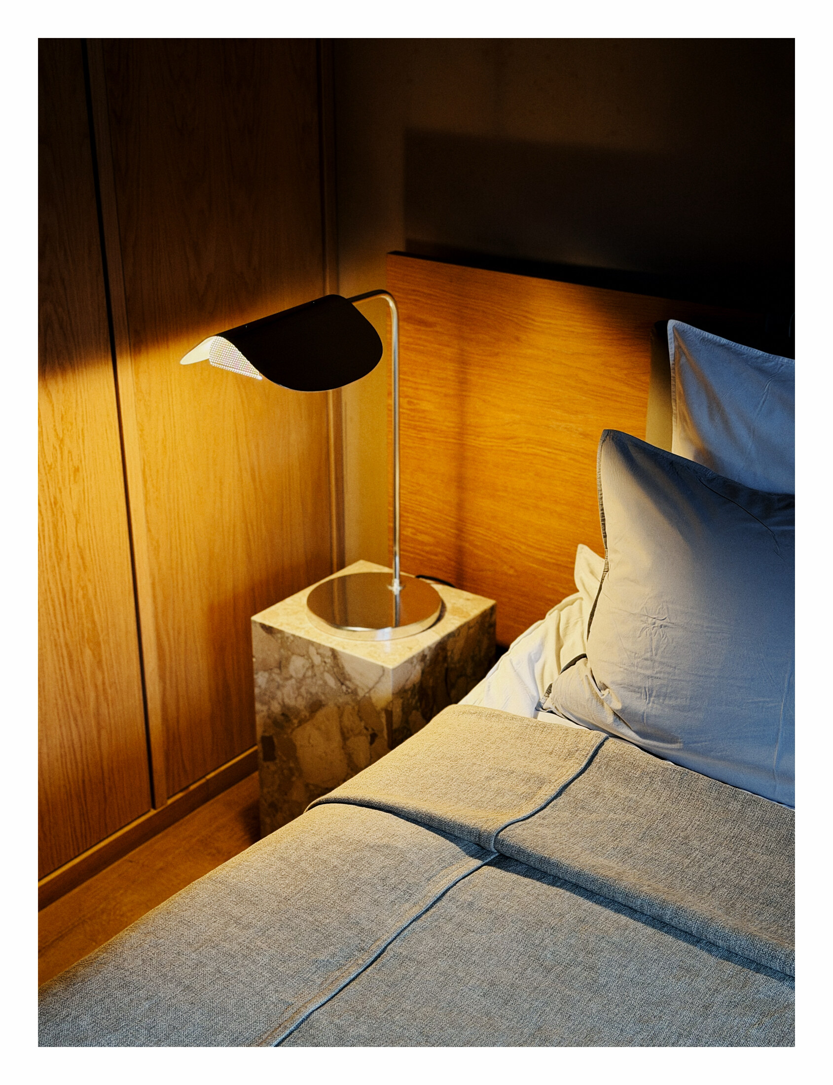 A quiet Audo Residence room with warm timber walls, a small stone table, and a pale bed